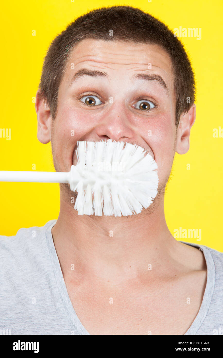 young-man-brushing-teeth-with-toilet-brush-D0TGNC.jpg